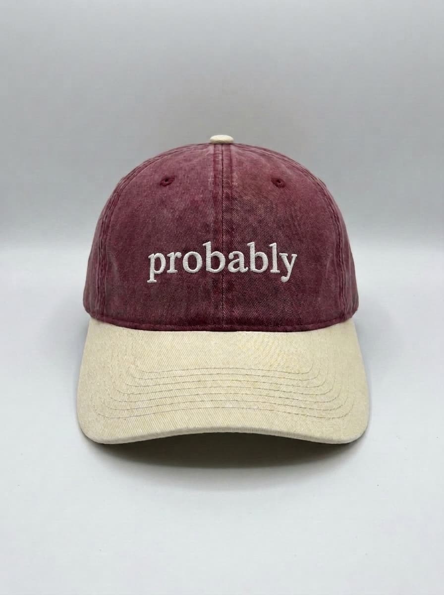 Maroon dad hat with a cream brim, embroidered in white with the lowercase word probably.